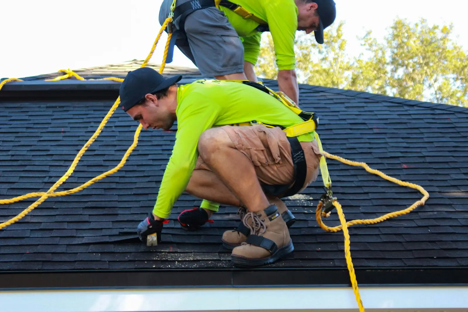 Roofers fastening a new shingle course